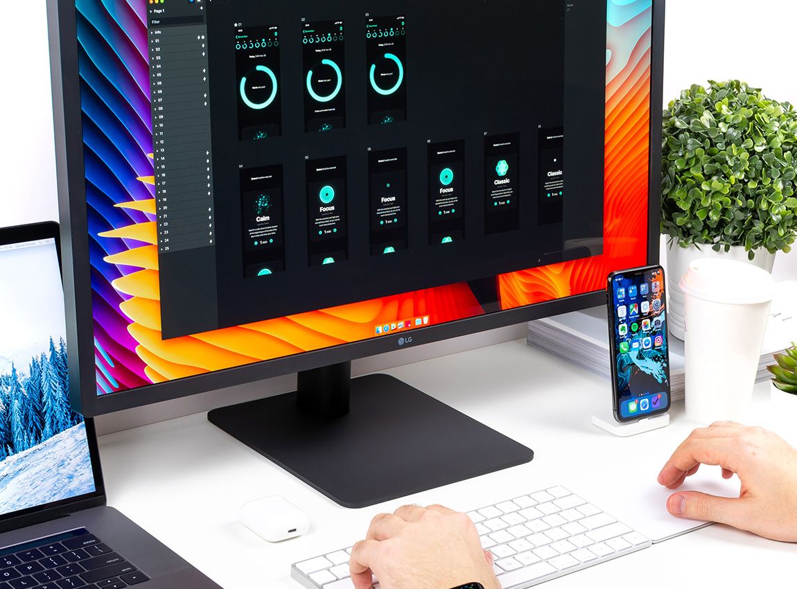 Desk with Macbook, monitor, iPhone and keyboard from Apple.