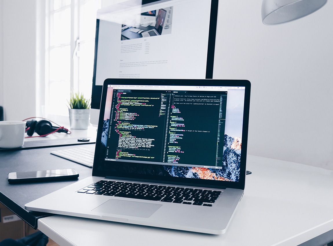 Macbook sitting on desk with code on screen. 