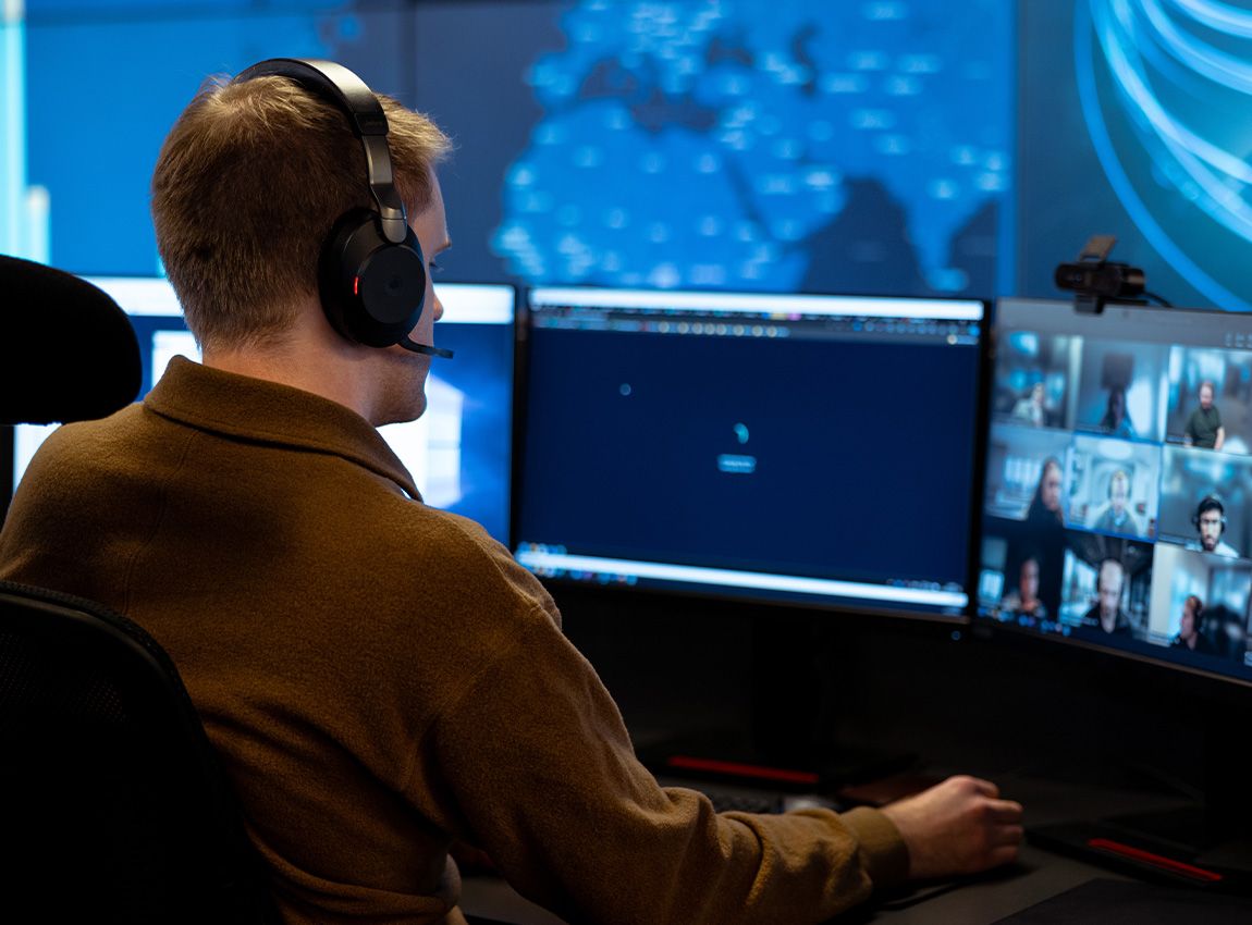 Mann med hodetelefoner som løser supporthenvendelser i en Teams-samtale.