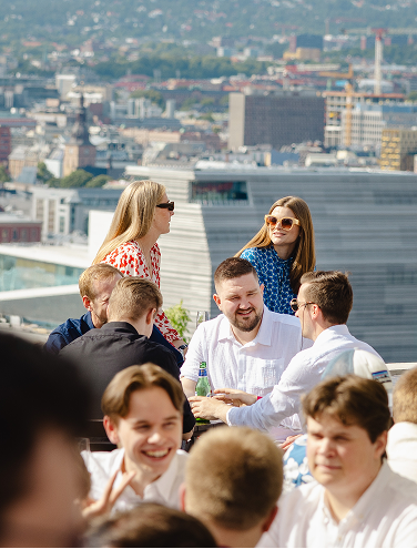 Personer samlade utomhus på takterrass med stadsutsikt i bakgrunden.